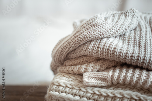 A stack of warm knitted items on blurred white background copy space.