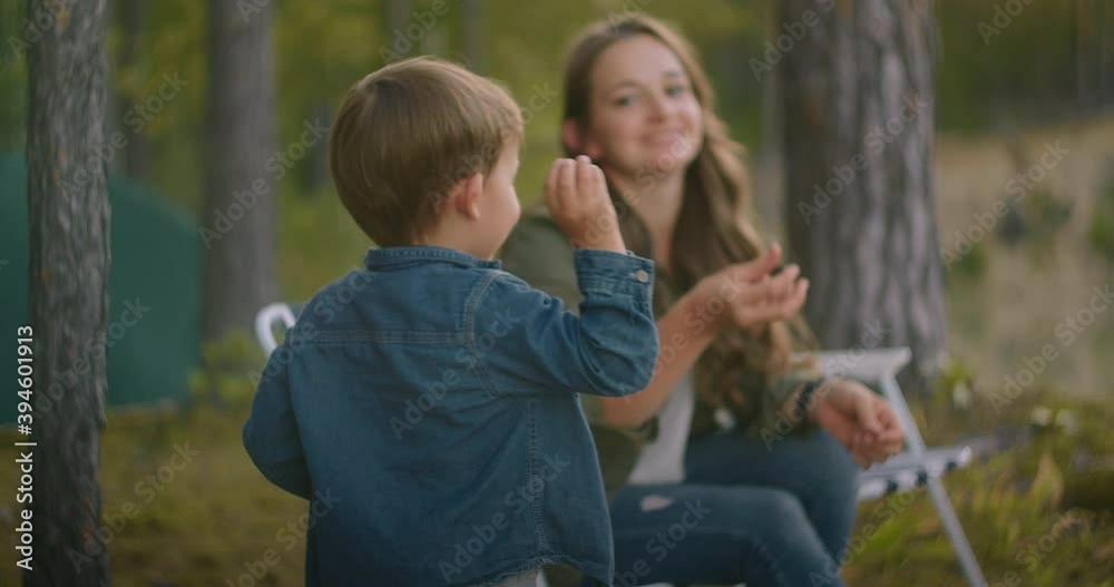 little boy with mother are throwing stones into water of lake, resting at nature at weekend, family travelling in forest little boy with mother are throwing stones into water of lake, resting at nature at weekend, family travelling in forest