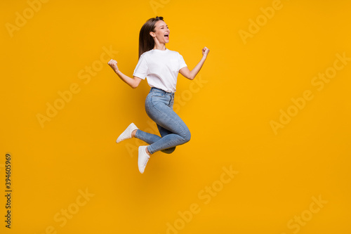 Full length body size photo of cheerful overjoyed girl fan jumping gesturing like winner yelling isolated bright yellow color background © deagreez
