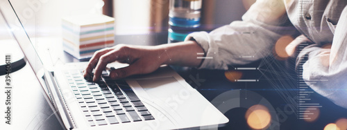 Woman with laptop distant working alone. Holding pen in hand and sitting at the desk. Remote studiyng at home. Graphic and stats effect overlay. Hands close-up wide screen photo