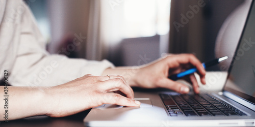 Woman with laptop distant working alone. Writing down with keyboard. Remote studiyng at home. Hands close-up wide screen