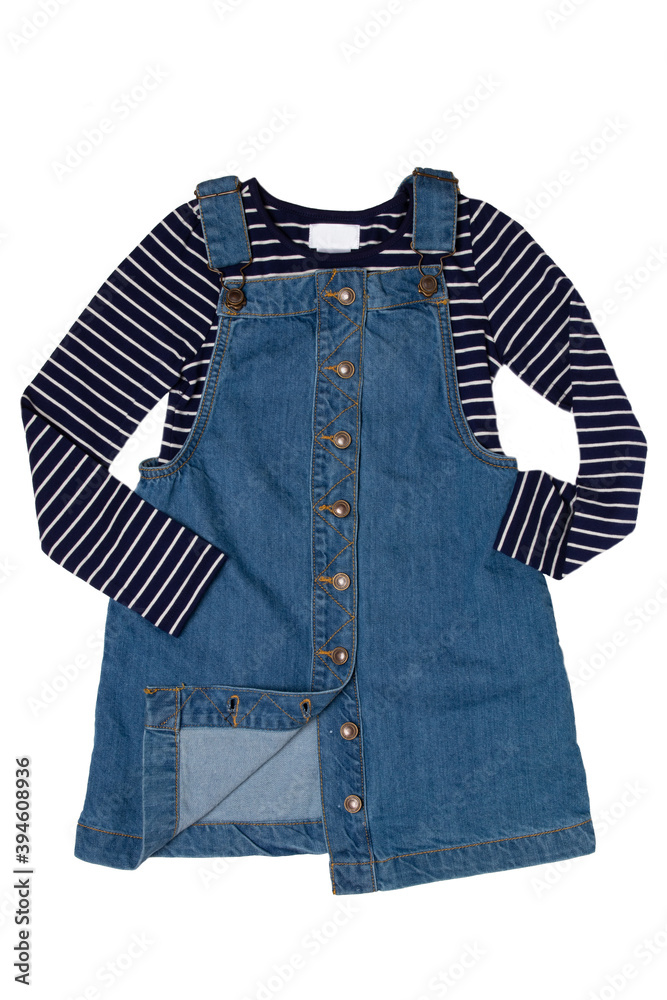 Closeup of cute sleeveless blue denim overall dress with striped t-shirt for little child girl isolated on a white background. Jeans fashion for kids. Closeup of cute sleeveless blue denim overall dress with striped t-shirt for little child girl isolated on a white background. Jeans fashion for kids.