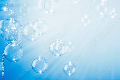 Abstract  Beautiful shiny transparent soap bubbles float on a blue texture background. Natural freshness summer holiday background.