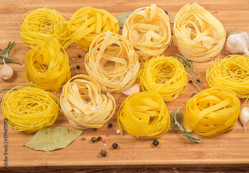 Different uncooked pasta nests among the spices on cutting board