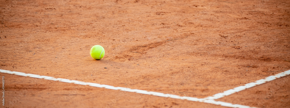 Tennis ball on red clay courts near defocused lines, competitive sport concept, no people