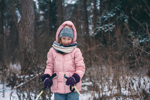 happy child girl skiing in winter snowy forest, spending holidays outdoor. Active winter sports.