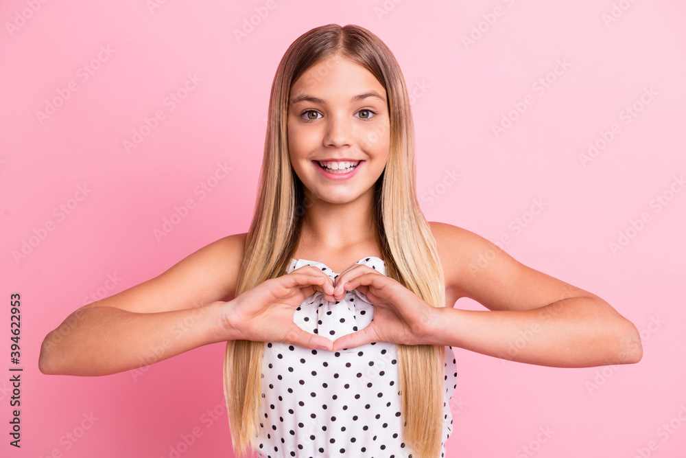 Portrait of sweet blond girl show heart sign wear white cloth isolated on pastel pink color background Portrait of sweet blond girl show heart sign wear white cloth isolated on pastel pink color background