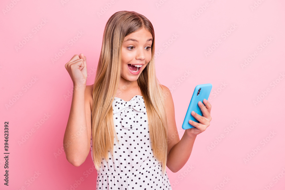Portrait of sweet impressed blond girl fist up hold telephone wear white cloth isolated on pastel pink color background Portrait of sweet impressed blond girl fist up hold telephone wear white cloth isolated on pastel pink color background