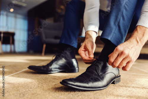 Closeup of a man tying a shoelace on his leather shoe. He is preparing to go on the work.