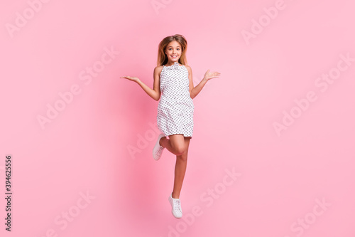 Full size photo of cute blond girl jumping wear white dress sneakers isolated on pastel pink color background