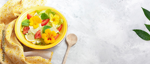 Banner with Fresh summer salad with edible flowers nasturtium, borage flowers in a bowl. Web banner, copy space. Vegan food. photo