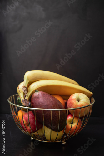 Fototapeta Naklejka Na Ścianę i Meble -  Tasty fruits in a metal basket. Wire basket with fruits on Black background. healthy eating concept