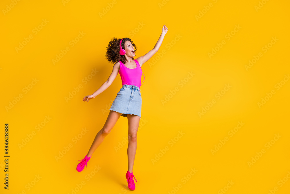 I can fly. Full body profile photo of beautiful lady jump up listen earphones hold hand imagine umbrella wear pink tank top mini denim skirt shoes isolated vivid yellow color background