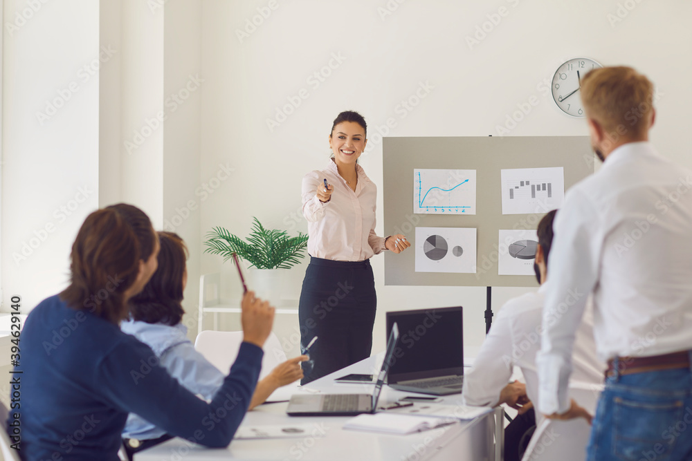 Happy young woman answering question while giving presentation in corporate meeting Happy young woman answering question while giving presentation in corporate meeting