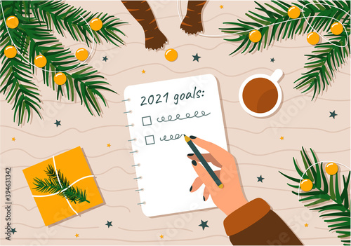 To-do list and goals for the New year. A woman's handwriting plans for the future surrounded by Christmas branches and Christmas decorations and cat paws stealing toys.