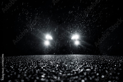 glowing car headlights at night in the rain