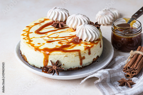 Vanilla cheesecake with carrot cake crust served with salty caramel topping and meringue, light concrete background. Selective focus.