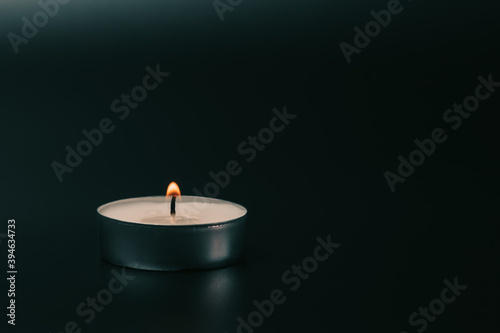 Small glowing candle on black background