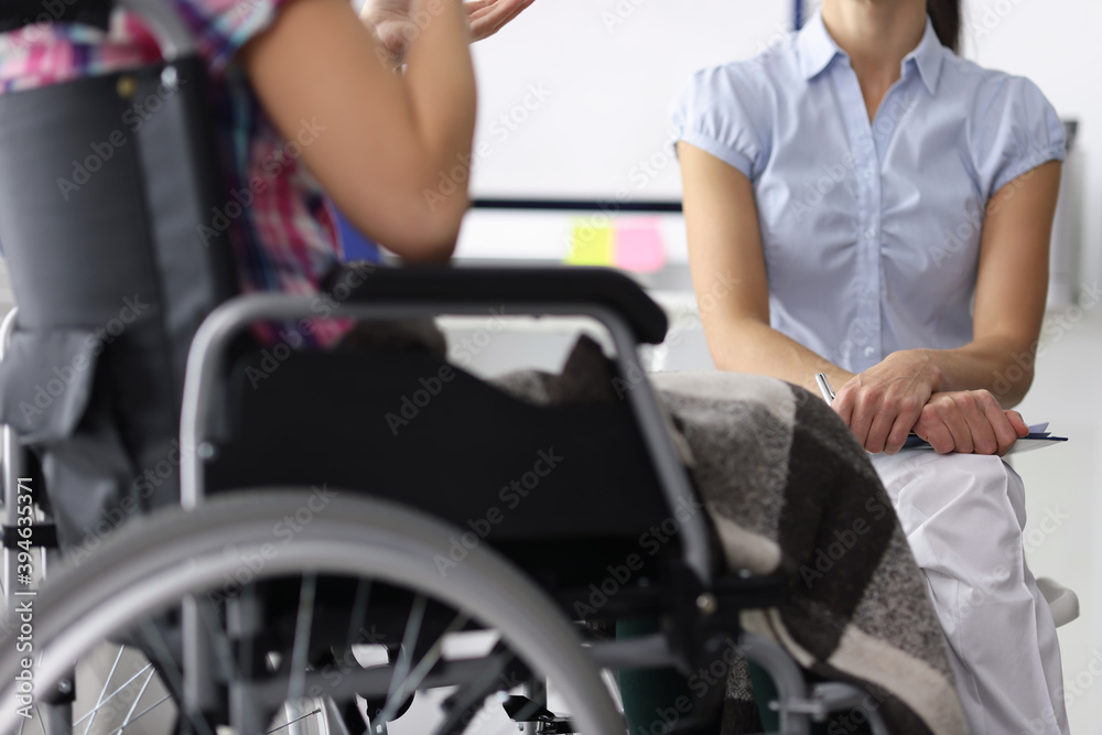 © H_Ko - Woman in a wheelchair in consultation with psychologist. Psychological assistance to people with disabilities concept