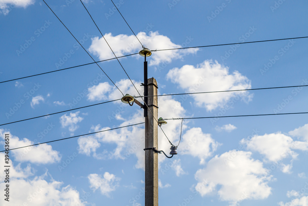 Electric concrete pole with wires. Background sky with light clouds. Metal constructions. Ceramic insulators. Electric concrete pole with wires. Background sky with light clouds. Metal constructions. Ceramic insulators.