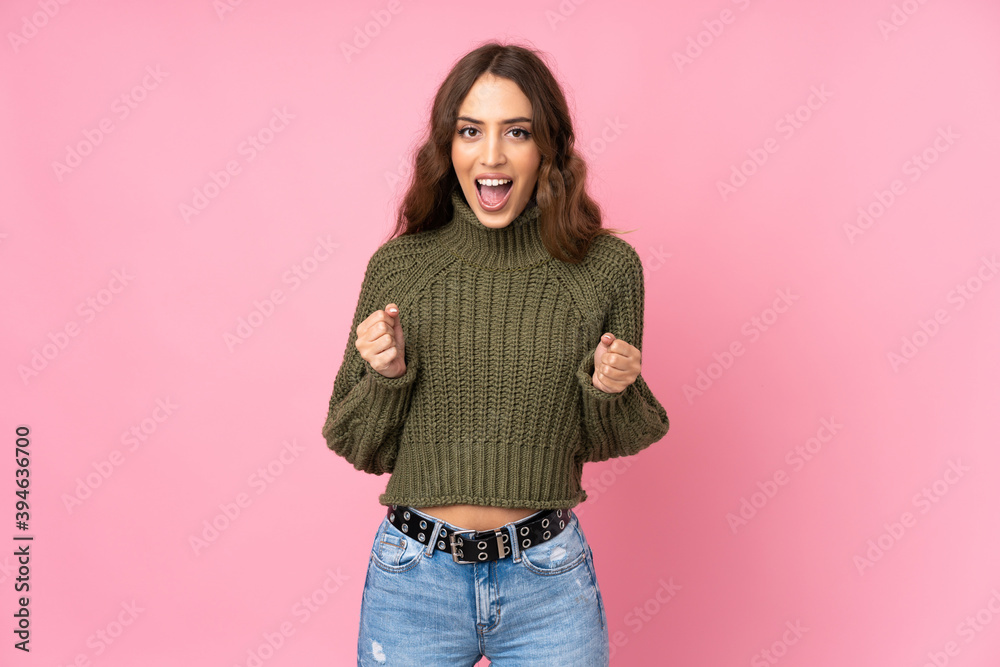 Young woman over isolated pink background celebrating a victory in winner position Young woman over isolated pink background celebrating a victory in winner position