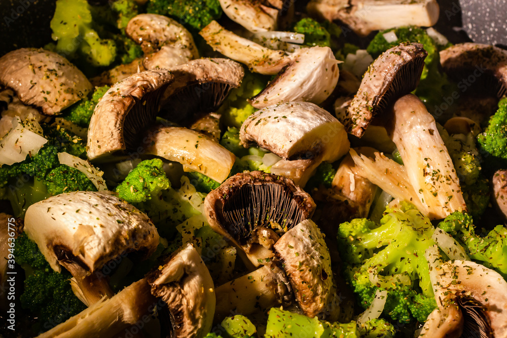 White champignons, onion and green broccoli fry on pan or wok. Hot delicious vegetarian dinner. White champignons, onion and green broccoli fry on pan or wok. Hot delicious vegetarian dinner.