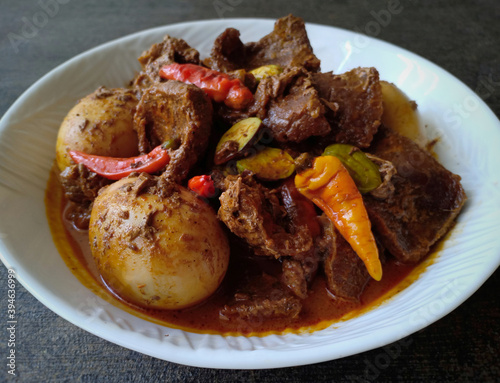Indonesian beef rendang with boiled eggs, red chilies, and petai. Rendang is an Indonesian spicy meat dish originating from the Minangkabau region in West Sumatra, Indonesia. Taste is spicy  photo