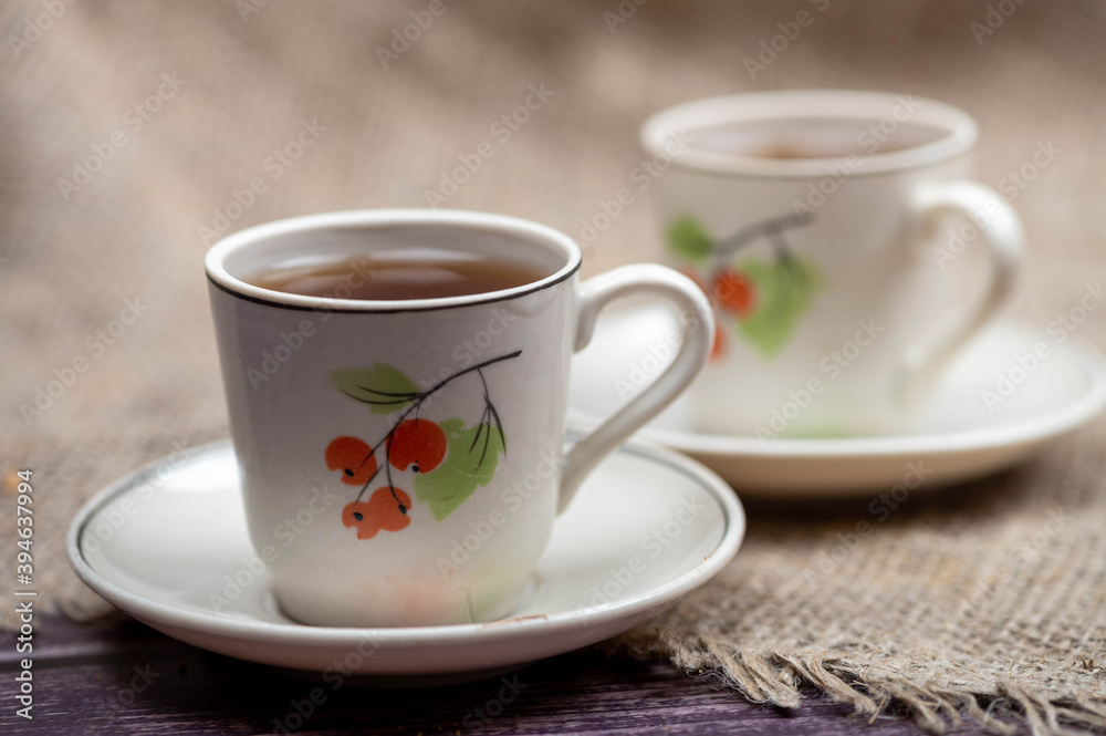 Two small mugs of tea on a background of coarse homespun fabric. Close-up, selective focus.