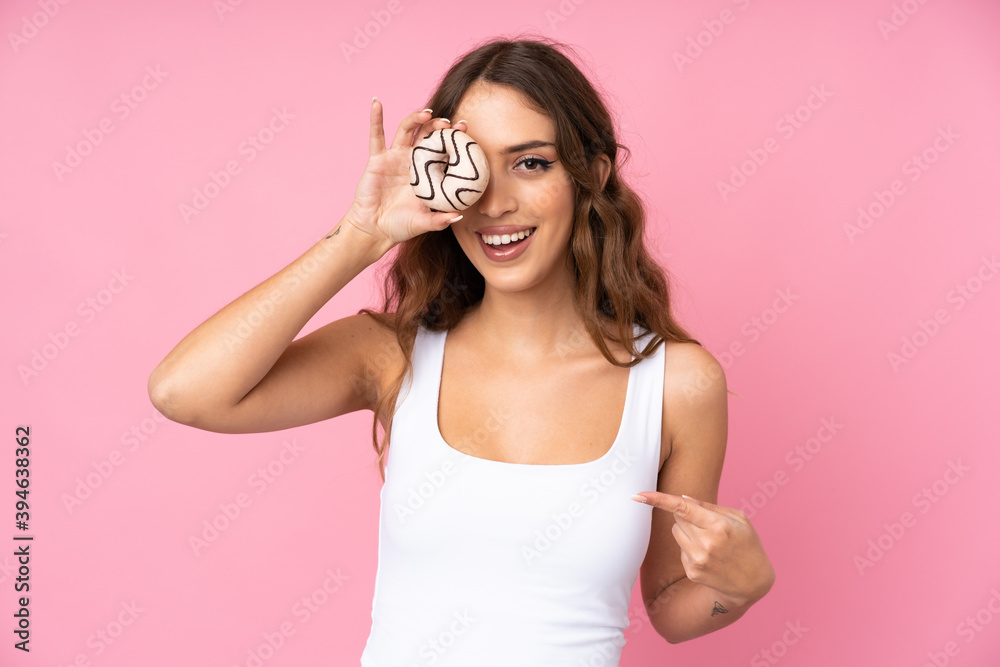 Young woman over isolated pink background holding a donut and happy Young woman over isolated pink background holding a donut and happy
