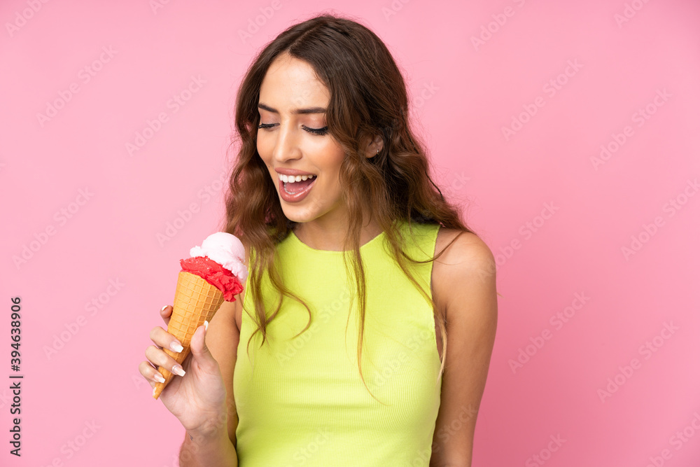 Young woman holding a cornet ice cream over isolated on a pink background Young woman holding a cornet ice cream over isolated on a pink background
