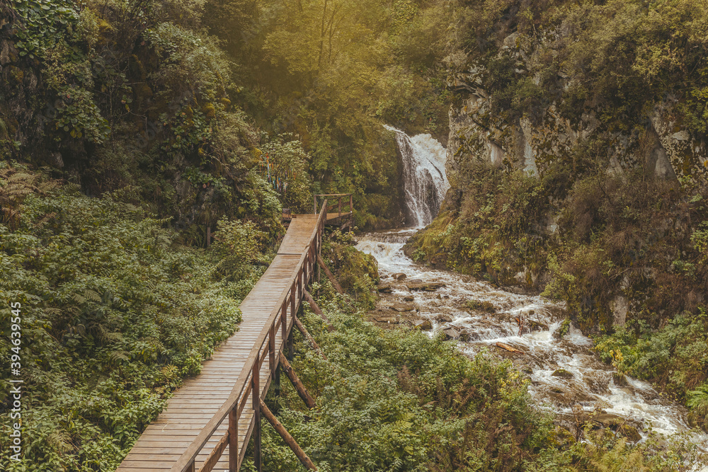 Landscape on a wooden long bridge and a waterfall. Wonderful nature and greenery. Plants are everywhere. Indescribable atmosphere. Nature concept Landscape on a wooden long bridge and a waterfall. Wonderful nature and greenery. Plants are everywhere. Indescribable atmosphere. Nature concept