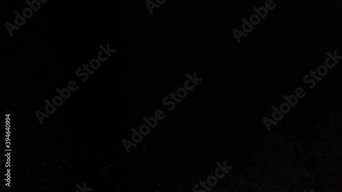 White spray on a dark background splashes on the left. Sneezing air drip particles, close-up.