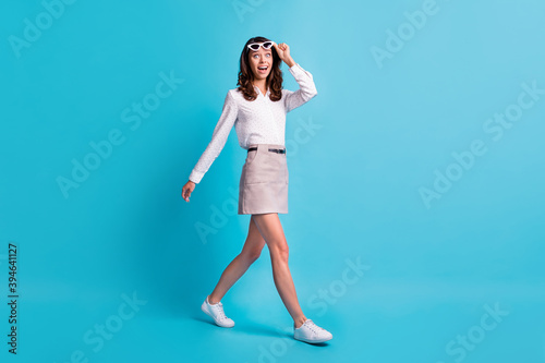 Full size profile photo of optimistic brunette girl go take off spectacles wear shirt skirt sneakers isolated on teal color background