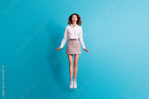 Full size photo of impressed brunette girl jump wear shirt skirt sneakers isolated on teal background