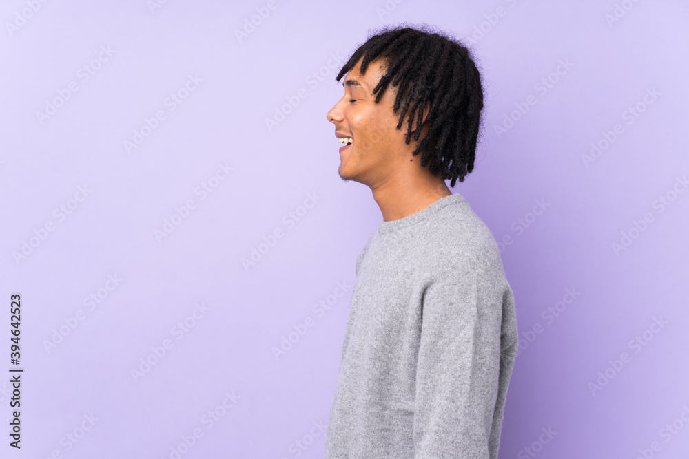 Young african american man isolated on purple background laughing in lateral position Young african american man isolated on purple background laughing in lateral position