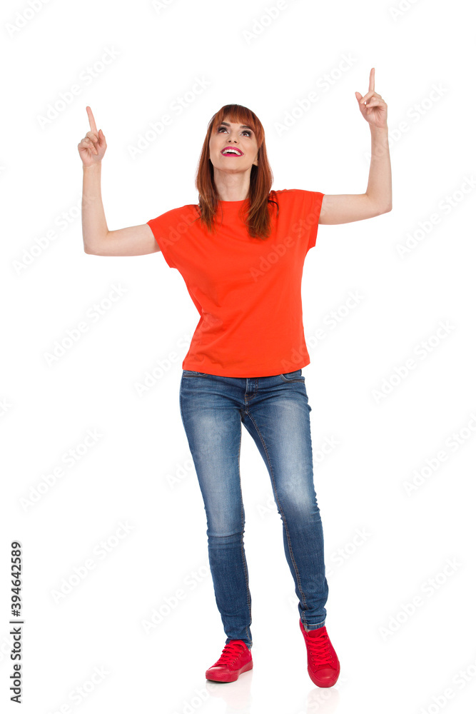 Casual Young Woman Is Standing, Looking Up And Pointing Casual Young Woman Is Standing, Looking Up And Pointing