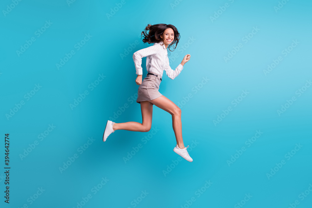 Full size profile photo of funny brunette girl jump run wear shirt skirt sneakers isolated on teal background Full size profile photo of funny brunette girl jump run wear shirt skirt sneakers isolated on teal background