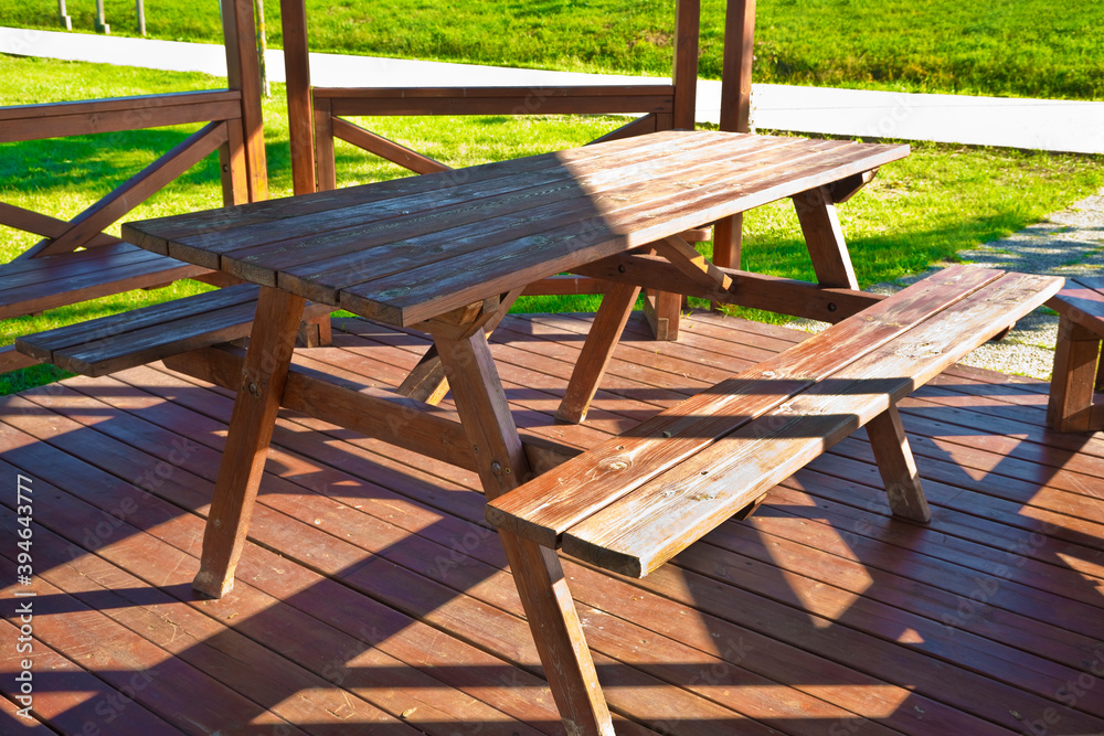 Wooden picnic table in a wooden gazebo on a green meadow in a public park Wooden picnic table in a wooden gazebo on a green meadow in a public park