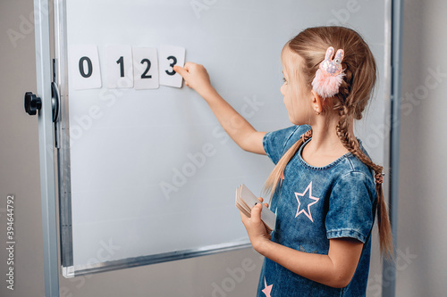 Portrait of a smart intelligent child arranging numbers in the correct order. Beautiful child holding a card with number 3. Study concept. photo with noise. photo with noise.