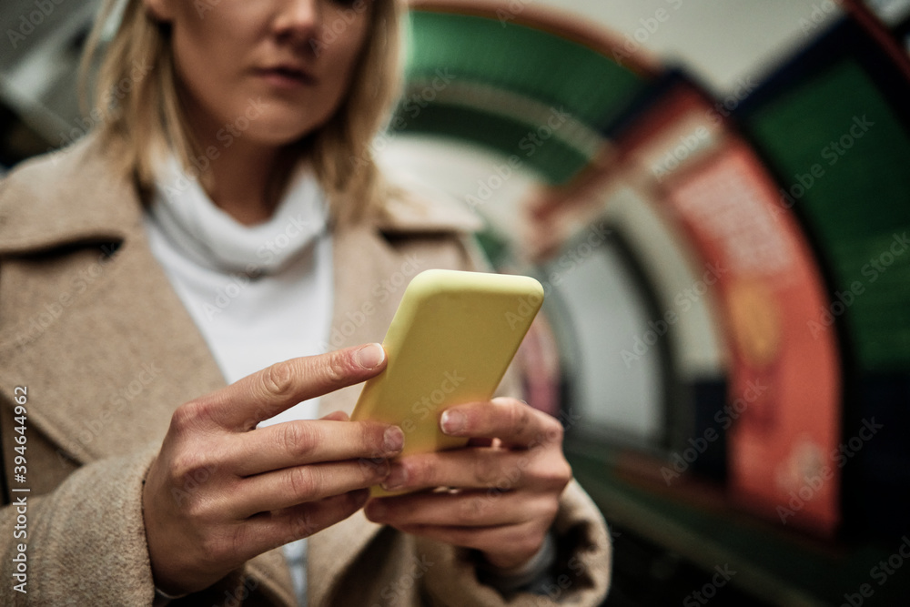 Blonde woman using a mobile phone on the tube underground station, London. Blonde woman using a mobile phone on the tube underground station, London.