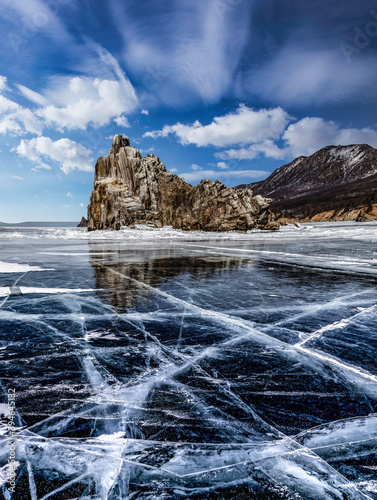 Cracks and bubbles on the surface of the ice frozen lake. Lake Baikal in winter   clear smooth ice near rocky shore.