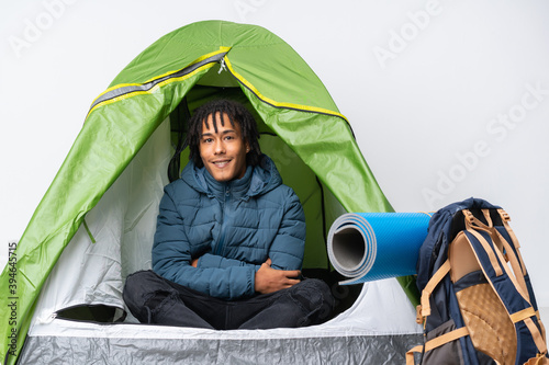 Young african american man inside a camping green tent keeping the arms crossed in frontal position