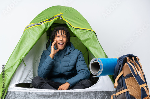 Young african american man inside a camping green tent with surprise and shocked facial expression