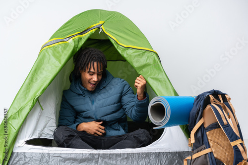 Young african american man inside a camping green tent making guitar gesture