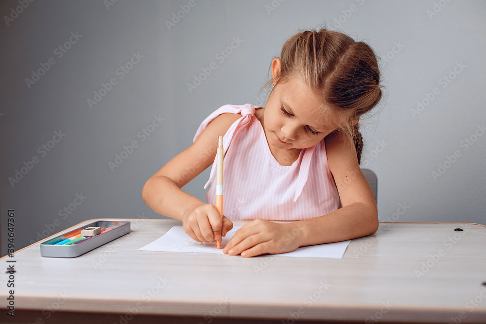 Portrait of a small neat diligent girl sitting at a table and drawing on paper with crayons. Childhood concept. photo with noise Portrait of a small neat diligent girl sitting at a table and drawing on paper with crayons. Childhood concept. photo with noise