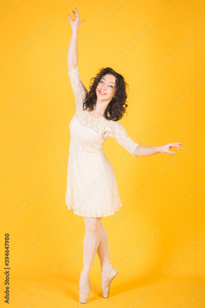 Graceful classic ballerina dancing on yellow studio Graceful classic ballerina dancing on yellow studio