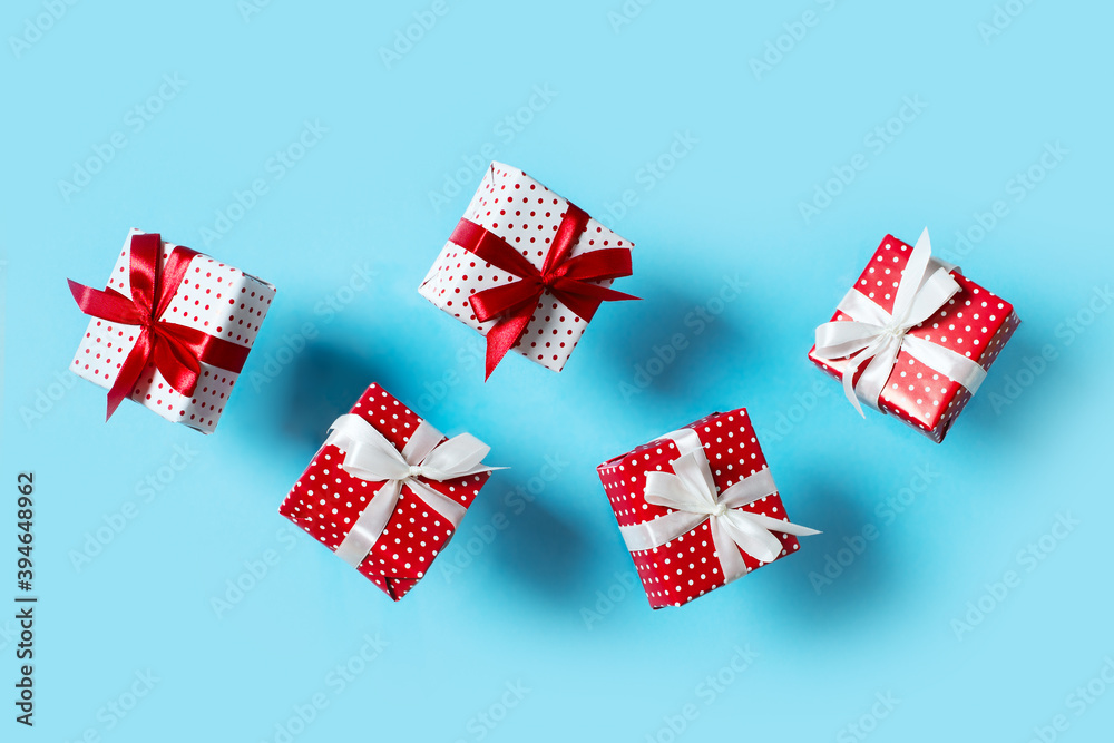 Fototapeta premium Polka dot pattern red gift box with ribbon and falling on blue background