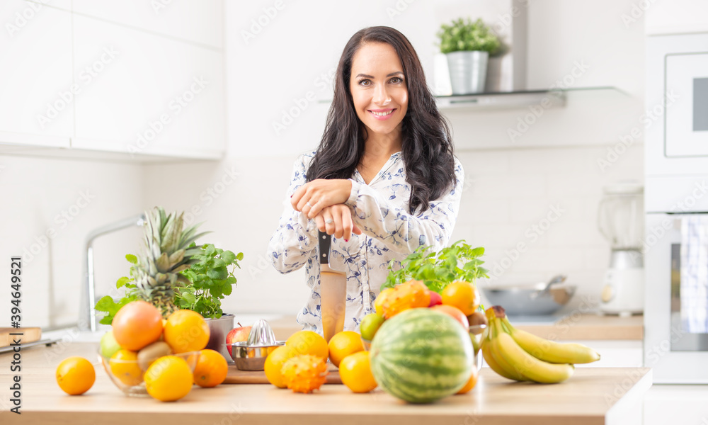 Smiling young woman holds a knife in the kitchen.