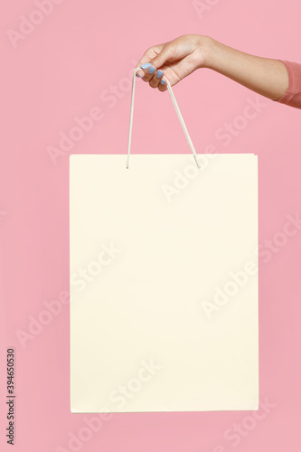 Hand of millennial african american female holding light paper shopping bag