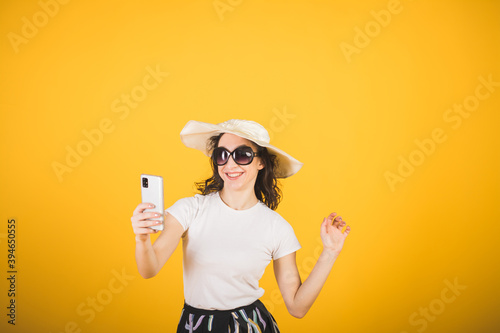 Stylish beautiful girl portrait on a yellow background with a phone